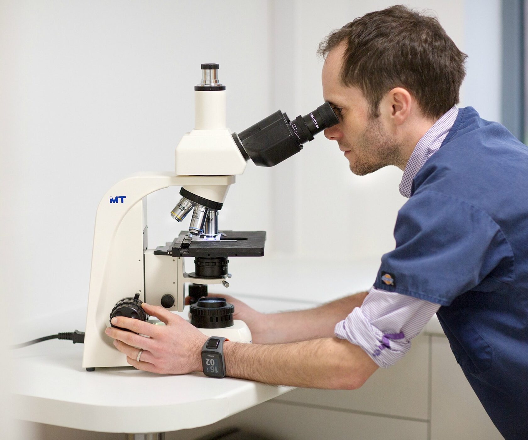 A vet examining a sample at the practice microscope